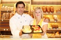 Baker and shopkeeper in bakery with tablet of cake Royalty Free Stock Photo