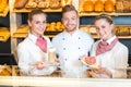 Baker and shopkeepers in bakery posing and presenting coffee and sandwiches Royalty Free Stock Photo