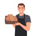 A baker smiling happily while holding an oven tray with freshly baked bread. Fresh bread smells good