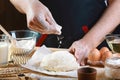 Baker sprinkle the dough with flour bread, pizza or pie recipe ingredients with hands, food on kitchen table background, working w Royalty Free Stock Photo