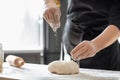 Baker sprinkling dough on kitchen table