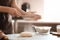 Baker sprinkling flour on dough at table