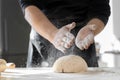 Baker sprinkling flour over dough on kitchen table