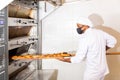 Baker taking baked bread out of oven on wooden shovel Royalty Free Stock Photo