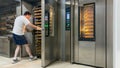 Baker taking freshly baked bread out of the oven. Bread fresh from the oven in a small bakery. Concept baker, bakery, bread. Royalty Free Stock Photo