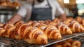 Baker in uniform examining fresh croissants on cooling rack in bakery