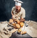 A baker wearing a uniform holding tray with freshly prepared products from his bakery