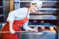 Baker woman getting fresh bread out of the oven Royalty Free Stock Photo