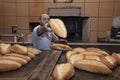 Baker. A young handsome bakery worker on the background of bread, takes bread from a stove with a wooden shovel. Industrial Royalty Free Stock Photo