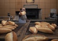 Baker. A young handsome bakery worker on the background of bread, takes bread from a stove with a wooden shovel. Industrial Royalty Free Stock Photo