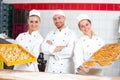 Bakers in bakery posing with baking tray