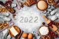 Bakery background with ingredients for cooking decorated with fir tree and new year 2022. Flour, brown sugar, eggs and spices Royalty Free Stock Photo