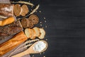 Bakery background top view. Crusty buns and loaves of bread on dark grey chalkboard background