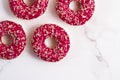 Frosted sprinkled donuts, sweet pastry dessert on marble table background, doughnuts as tasty snack, top view food brand flat lay