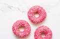 Frosted sprinkled donuts, sweet pastry dessert on marble table background, doughnuts as tasty snack, top view food brand flat lay