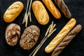 Bakery concept. Fresh white and brown bread. Loaf and baguette decorated with wheat ears on black background top view Royalty Free Stock Photo