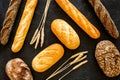 Bakery concept. Fresh white and brown bread. Loaf and baguette decorated with wheat ears on black background top view Royalty Free Stock Photo