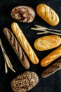 Bakery concept. Fresh white and brown bread. Loaf and baguette decorated with wheat ears on black background top view Royalty Free Stock Photo