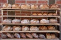 Bakery products. A variety of fresh baked breads in wooden shelves of a country bakery in front of a brick wall. Concept healthy Royalty Free Stock Photo
