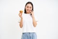 Bakery and sweets. Happy asian woman looking at tasty cupcake, eating pastry, white background
