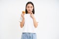 Bakery and sweets. Happy asian woman looking at tasty cupcake, eating pastry, white background