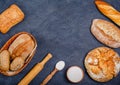 Bakery - various rustic crispy buns with bread and rolls, wheat flour, a bunch of spikelets on a dark background