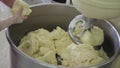 The bakery worker hands helps stir the dough in the kneader.