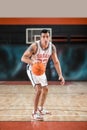 Dark-haired athletic man playing basket-ball in the gym