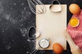 Baking background with flour, rolling pin, eggs, paper sheet and heart shape on kitchen black table from above for Valentines day.