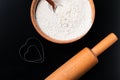 Baking background with flour, rolling pin and heart shape on dark table with copy space, top view. Valentines day cooking concept Royalty Free Stock Photo