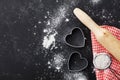 Baking background with flour, rolling pin and heart shape on kitchen black table top view for Valentines day cooking. Flat lay. Royalty Free Stock Photo