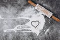 Baking background. Heart of flour and rolling pin on gray table. Bake menu, recipe, homemade pastry concept. Top view.