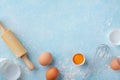 Baking background with rolling pin, whisk, eggs, flour on blue table top view. Flat lay Royalty Free Stock Photo