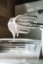 Baking concept. Whipped cream of egg whites for perfect peaks in a glass bowl, with a mixer on a marble white table. Meringue