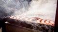 Baking delicious juicy sausages on the big barbecue plate, smoky view