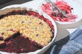 Baking dish with blueberry cobbler next to an empty dish with forks. eaten part of a cake. crumble berry cake