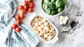 Baking dish of raw conchiglie pasta with cheese, tomatoes and spinach on light background Royalty Free Stock Photo