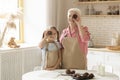 Baking is fun. Senior lady and her grandchild with chocolate muffins being silly in kitchen, copy space