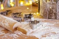 Baking gingerbread cookie cutters, wooden rolling pin, and flour are messily spread on kitchen table Royalty Free Stock Photo
