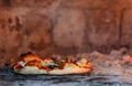 Baking home made pizza inside a wood fired oven. Selective focus Royalty Free Stock Photo