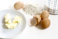 Baking ingredients, butter, eggs, flour and milk on a white back