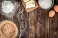Baking ingredients for cooking chocolate waffles or cake. Bowl with sugar, eggs, flour, butter on dark wooden background. Royalty Free Stock Photo
