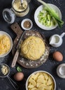 Baking ingredients - dough, potatoes, cheese, leek, cream. Cooking pie with leek, potato and cheese. On a dark background