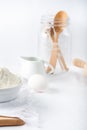 Baking ingredients. White background. Ingredients and tools to make a cake. Flour, milk, eggs, rolling pin, wooden spoons, jar. Royalty Free Stock Photo