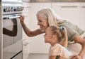 Baking, kitchen and grandmother with a child by the oven watching the cake, cookies or pie bake. Happy, smile and senior Royalty Free Stock Photo