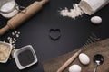 Baking love. Bakery background. Baking ingredients and kitchen utensils on the black background. Flour, almond nuts, eggs. Top