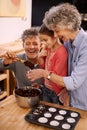 Baking is more fun as a team. a little girl and her grandparents making cupcakes in the kitchen.