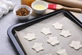 Baking pan with unbaked homemade cookies and parchment paper on light grey table