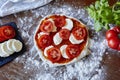 Baking pizza rolled out dough sauce tomatoes and mozzarella