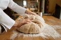 Baking process, closeup baker hands kneading dough on table